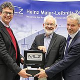 Drei Personen mit einer Trophäe des MLZ