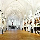 Flur einer Bibliothek mit Bücherregalen und kleinen Statuen